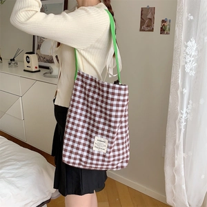 Détail d'un sac cabas en toile à carreaux avec anses vertes et étiquette tissée