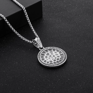 Detailed close-up of a vintage hammered texture stainless steel round pendant on a chain