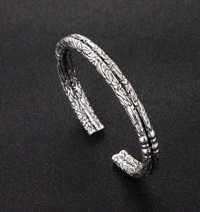 Macro shot of silver vintage open cuff bracelet featuring intricate relief snake textures