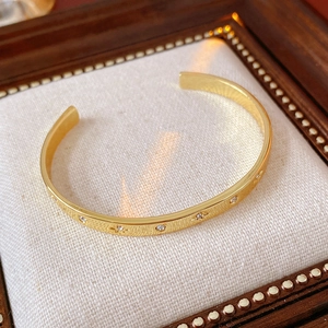 Détail d'un bracelet jonc doré avec gravures d'étoiles et zircon incrusté
