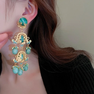 Détail rapproché des boucles d'oreilles vintage dorées avec fleurs en résine et gemmes
