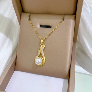 Close-up of luxury gold pendant featuring pavé crystals and a large white pearl