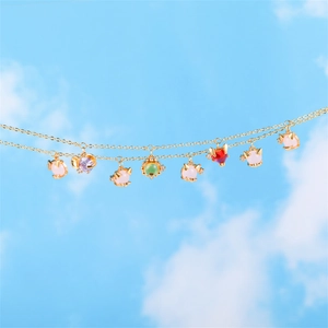 Close-up of a gold necklace with colorful cat and heart charms against a blue sky