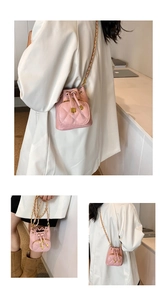Three-way view of a pink quilted mini bucket bag with gold chain strap on a white blazer