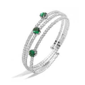 Detail view of silver multi-layer bracelet with clear diamonds and green emerald stones