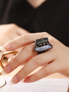 Close-up of vintage bronze open ring with raw black and blue stones on hand