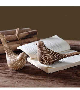 Detail of resin bird figurines with white faux wood grain patterns on rustic wood