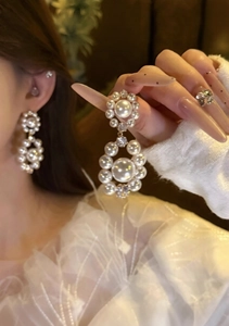 Close-up of vintage floral stud earrings with round pearl charms worn by a model