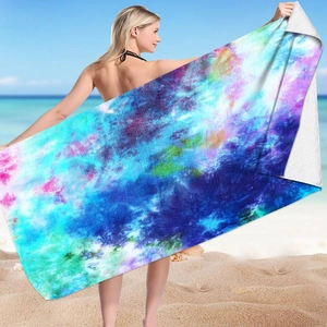 Microfiber beach towel with vibrant tie-dye galaxy print held by a model on a sandy beach