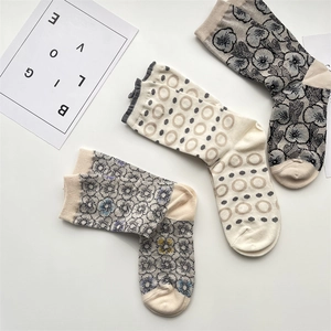 Detail of three pairs of vintage floral jacquard socks in beige and grey cotton blend