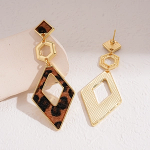 Detail showing geometric leopard print earrings with gold metallic finish on textured stone