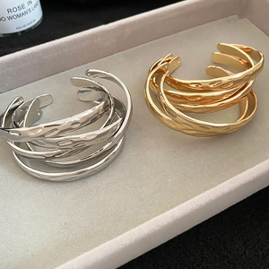Detail of layered metal bangle bracelets with textured hammered finish in gold and silver