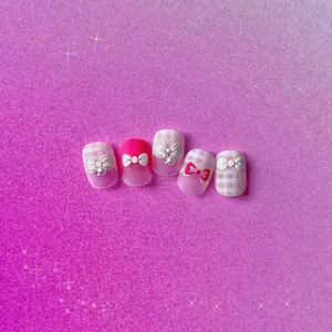 Close-up of pink 3D embossed nail stickers featuring bows and pearl accents
