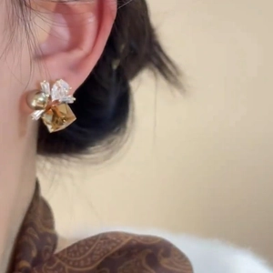 French vintage gold earrings with amber gems and pearls worn by a model in close-up shot