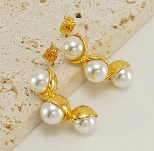 Detail shot of gold earrings featuring three elegant pearls in a curved design