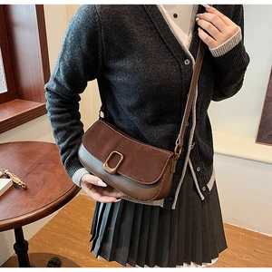 Detail view of brown patchwork underarm bag with golden square lock and suede flap