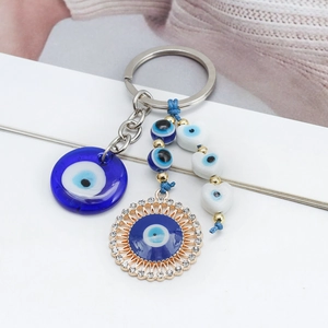 Detail of blue Evil Eye keychain with Hamsa hand charms and white heart beads decor