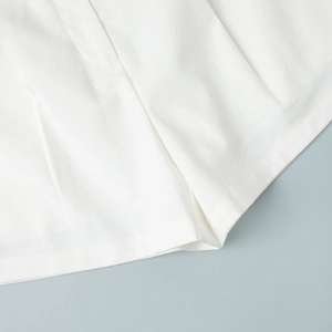 Detailed close-up of white linen-blend shorts showing high-quality stitching and fabric texture
