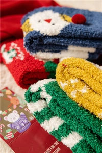 Close-up of soft coral fleece Christmas socks with festive patterns in a gift box