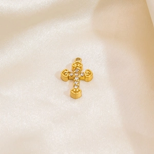 Minimalist gold stainless steel cross pendant with zircon stones on satin background