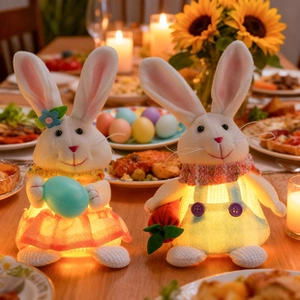 Primer plano de conejitos de Pascua de tela luminosos con huevos y zanahorias de mesa
