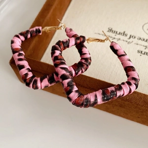 Detailed close-up of pink leopard print square hoop earrings with golden metal hooks