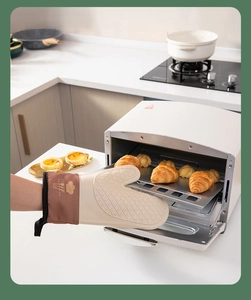 Silicone heat resistant oven mitt taking out fresh croissants from a modern electric oven