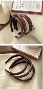 Macro view of high-quality burgundy PU sponge headband with metal logo and bow detail