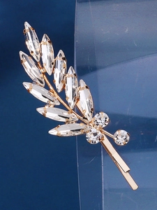 Detail shot of a golden leaf-shaped bridal hair clip with sparkling marquise rhinestones