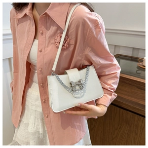Detail of white leather shoulder bag with silver metal bow and chunky chain handle