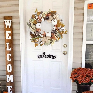 Autumn wreath with white pumpkins, pine cones and maple leaves on a white front door
