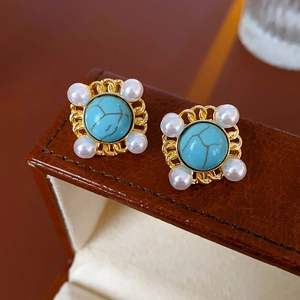 Detail of vintage turquoise and pearl earrings on a premium brown leather jewelry box