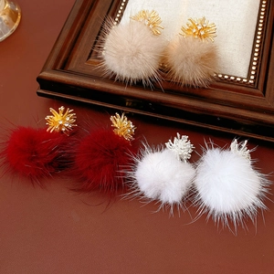 Close-up of fluffy pom pom earrings in beige, red, and white with zircon accents