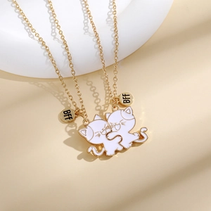 Detail of two gold chain necklaces with white enamel split cat pendants and BFF charms