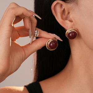 Boucles d'oreilles vintage avec bobines dorées et perles rouge foncé sur modèle