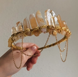 Close-up of golden crystal crown with yellow stones, metal chains, and sun pendant