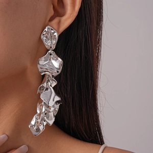 Macro detail of irregular pleated silver petals long earrings on model with metallic finish