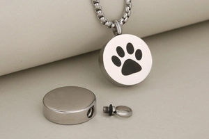 Detail of silver round pet urn pendant with black paw print and screw opening