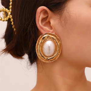 Detail of vintage wavy gold earring with large white pearl on model's ear