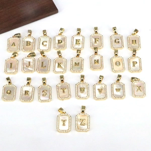 Detailed view of 26-letter 18K gold rectangle pendants with shell inlay and zircon accents