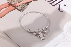 Vue détaillée d'un bracelet réglable en acier avec pendentif garçon et petites cloches