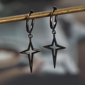 Macro shot of minimalist black star pendants on round hoop earrings hanging on a metal bar