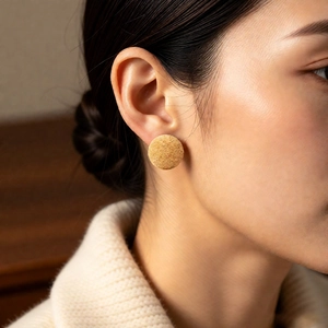 Close-up of minimalist round earring with frosted texture worn by a model
