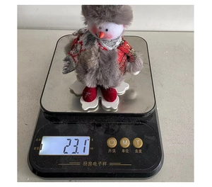 Close-up of plush Christmas snowman ornament on a scale showing its weight of 23.1g