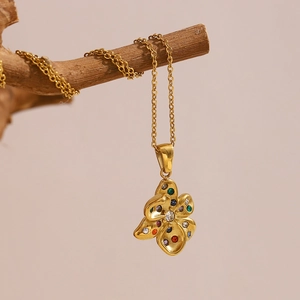 Détail macro du pendentif fleur en or 18K avec pierre colorée sur une branche