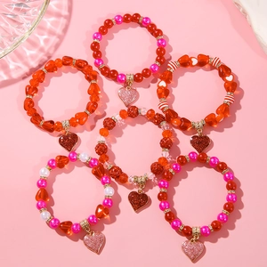 Close-up of 6-piece beaded heart bracelets set with red and pink acrylic pearls