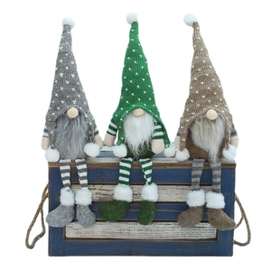 Three handmade Christmas gnomes with knitted hats and long legs on a rustic wooden box