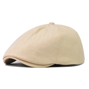 Detail shot of beige newsboy hat featuring textured herringbone fabric and button top