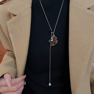 Silver long necklace with brown rocking horse pendant and pearls on khaki blazer model