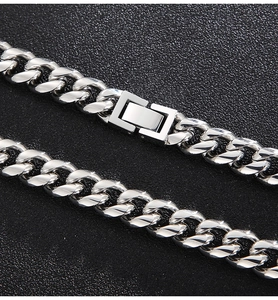Macro shot of silver Cuban link chain with a polished box clasp on dark texture